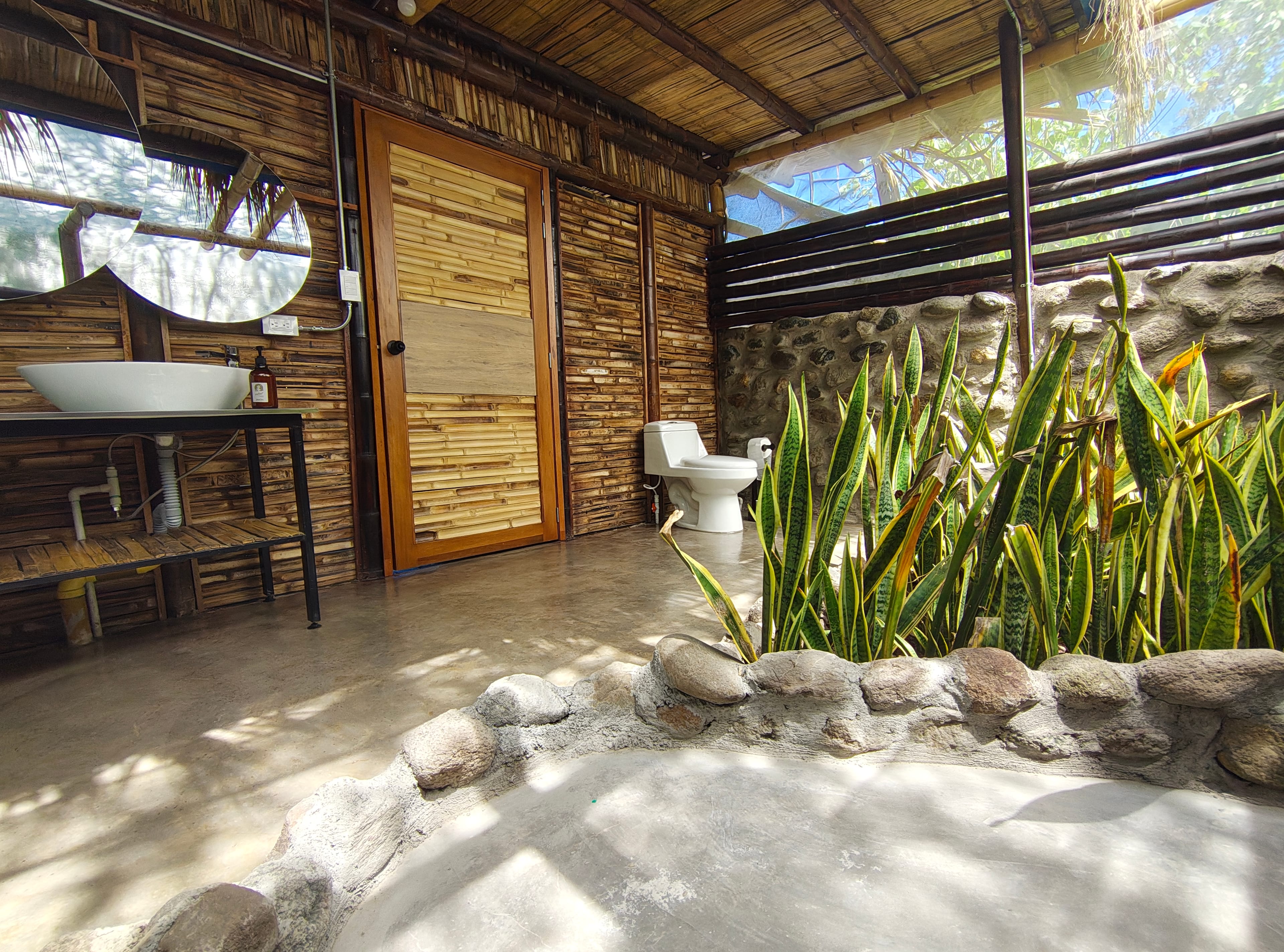 Baño privado al aire libre con jardín de plantas y construcción en piedra