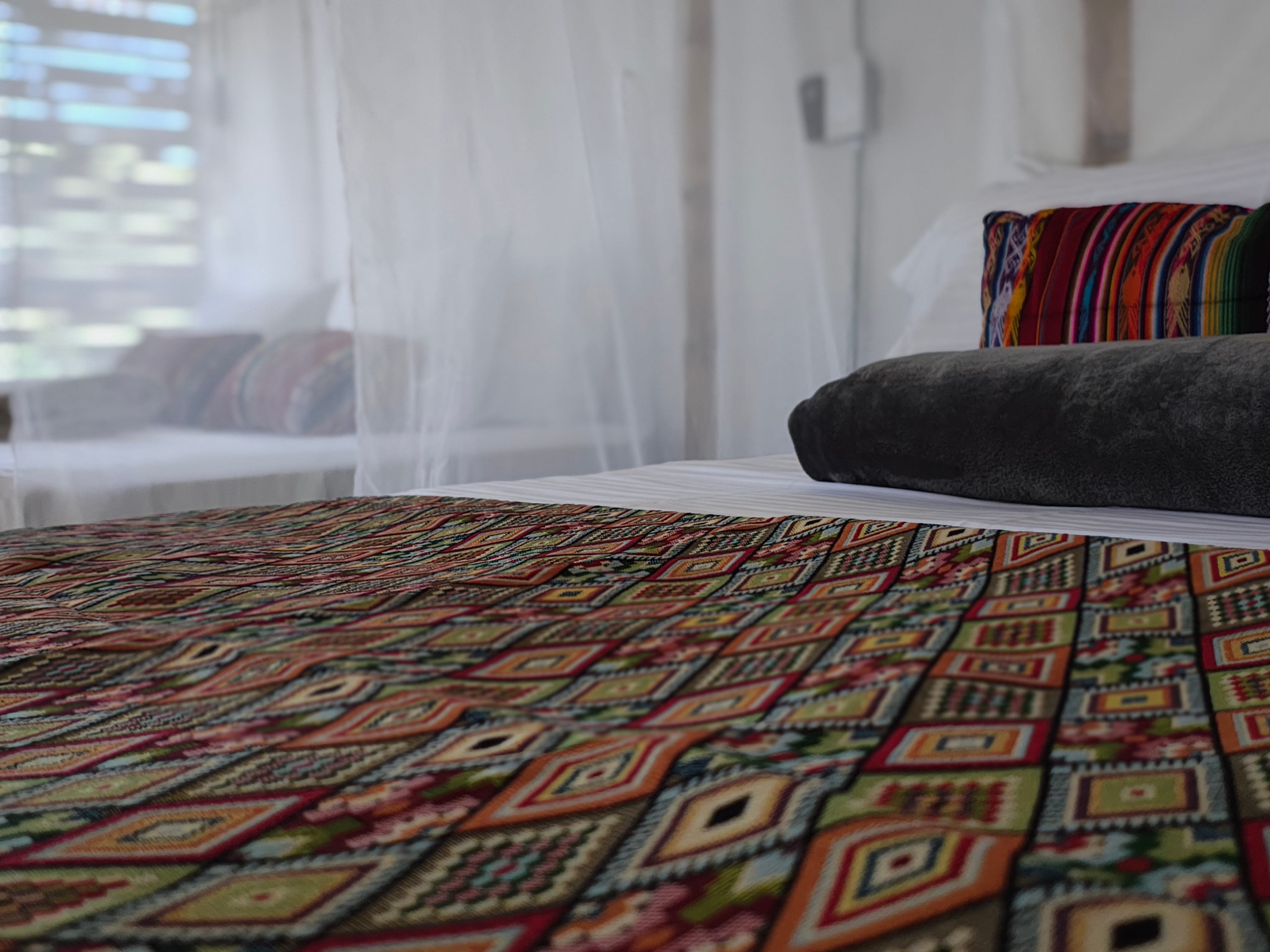 Detalle de cama con cobija artesanal colombiana y toallas de lujo