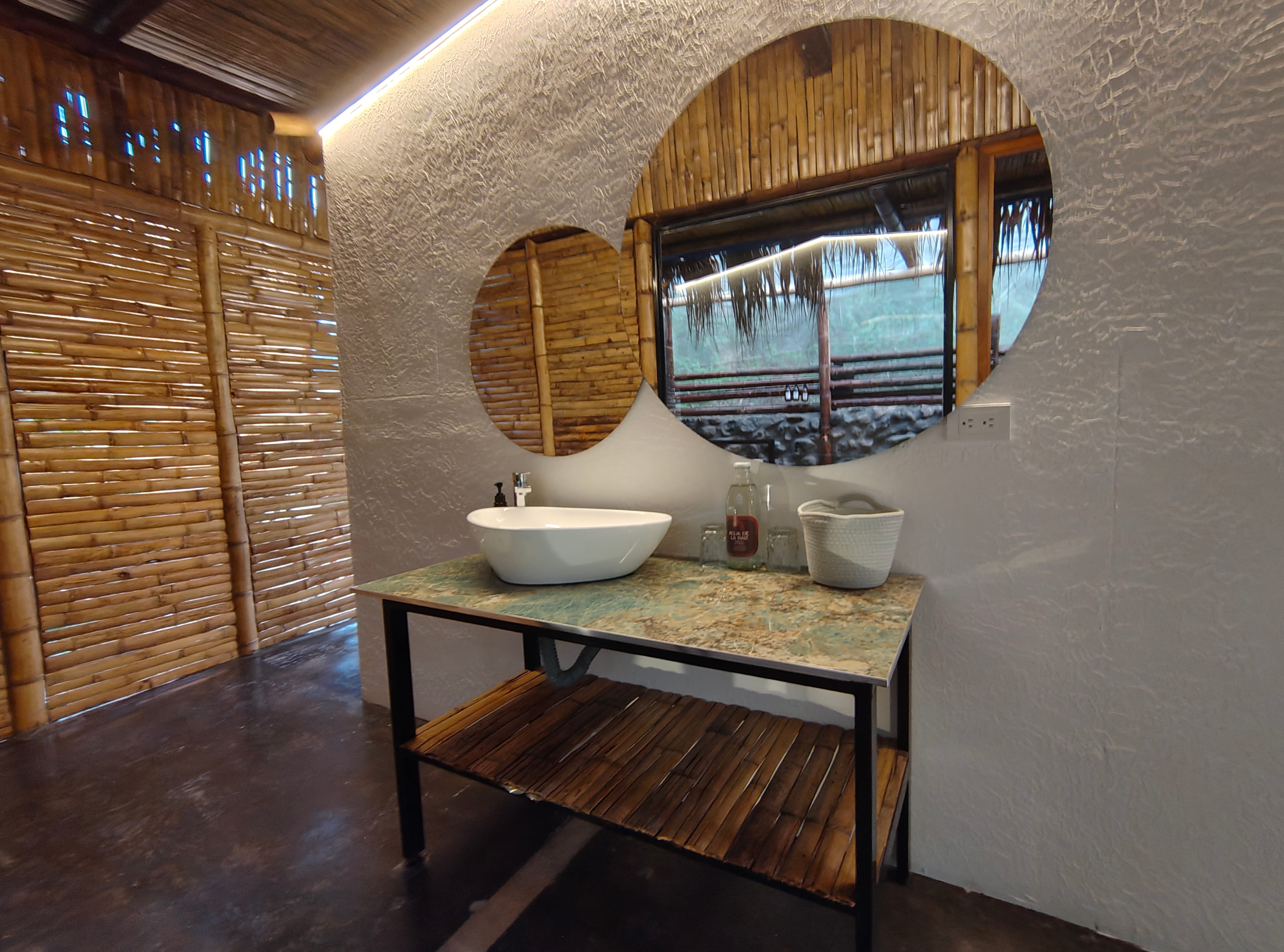 Lavamanos con espejos circulares de bambú y diseño moderno en baño semiabierto